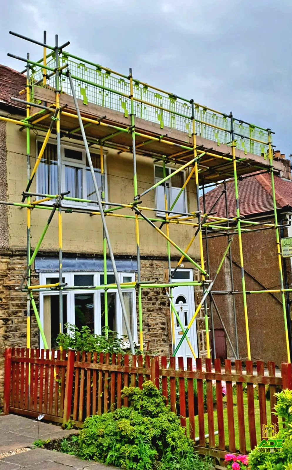 Single-lift eaves scaffold with green debris mesh on a render semi
