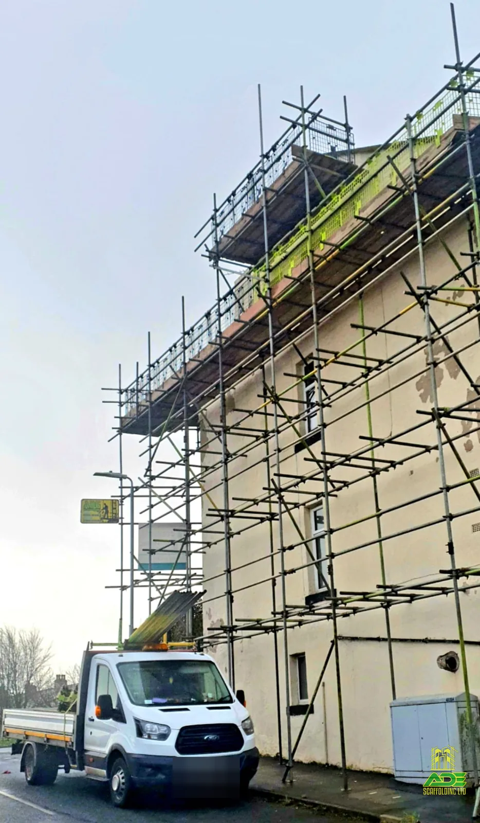Three-lift gable scaffold for render repair with ADE tipper on site